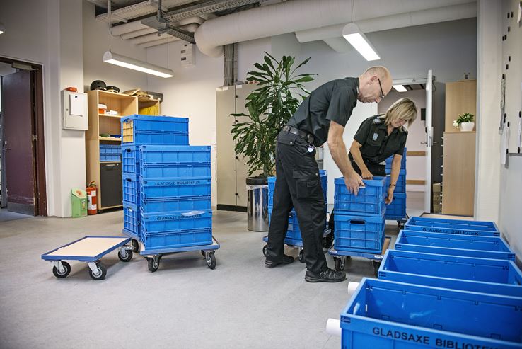 To biblioteksbetjente - en mand og en kvinde - er ved at pakke bøger i kasser